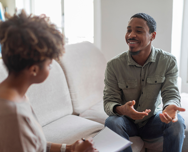 A counselor sits smiling and providing guidance to an attentive patient.