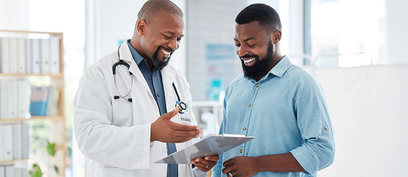 Doctor and patient smiling while looking at a clipboard reviewing information