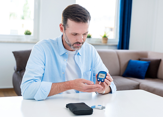 Person sitting inside using a blood glucose monitor to manage their diabetes