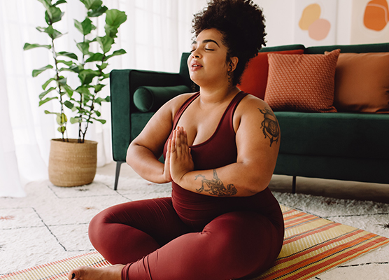 Woman in red exercise clothing doing yoga on a patterned yoga mat