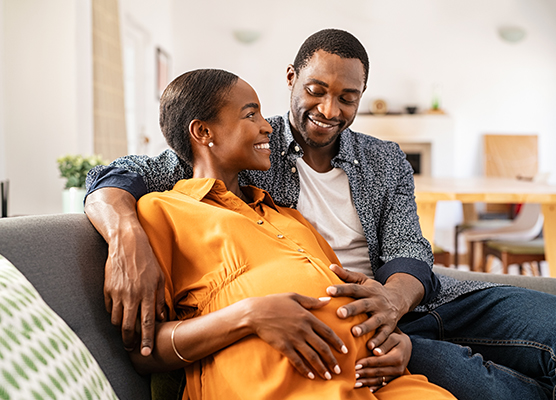 Couple sitting together with hands on the woman's pregnant belly