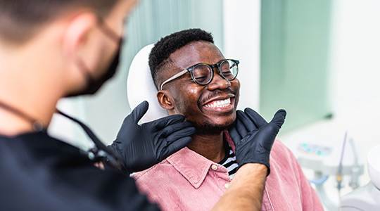 Male dental patient smiling in a dental chair during a visit, showing how routine dental care helps support healthy teeth and overall wellness.