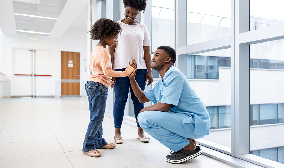 Nurse high fiving child patient with mother standing to the side