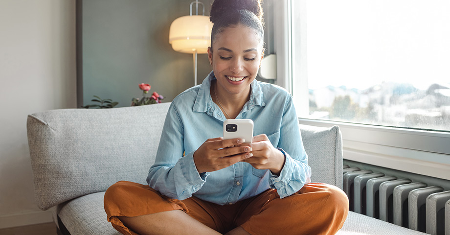 Young woman smiling while looking at her smartphone.