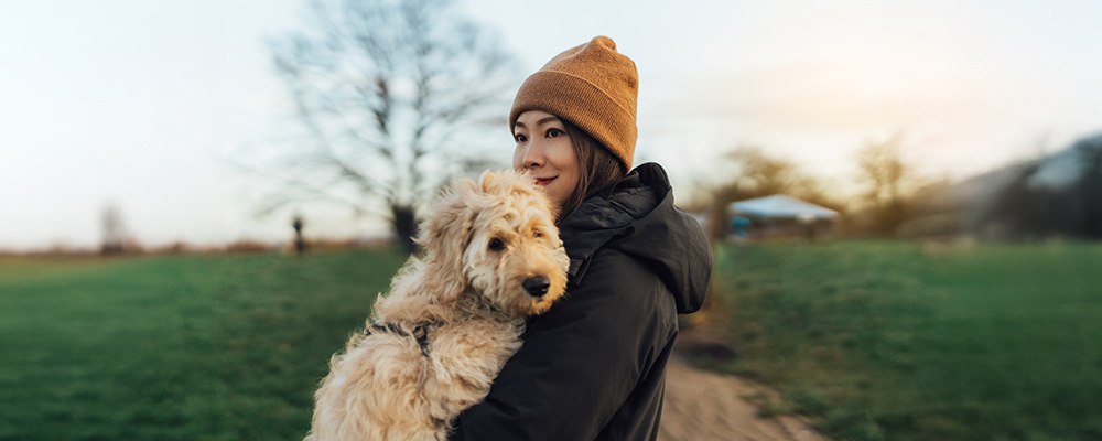 Woman holding dog in arms out in country