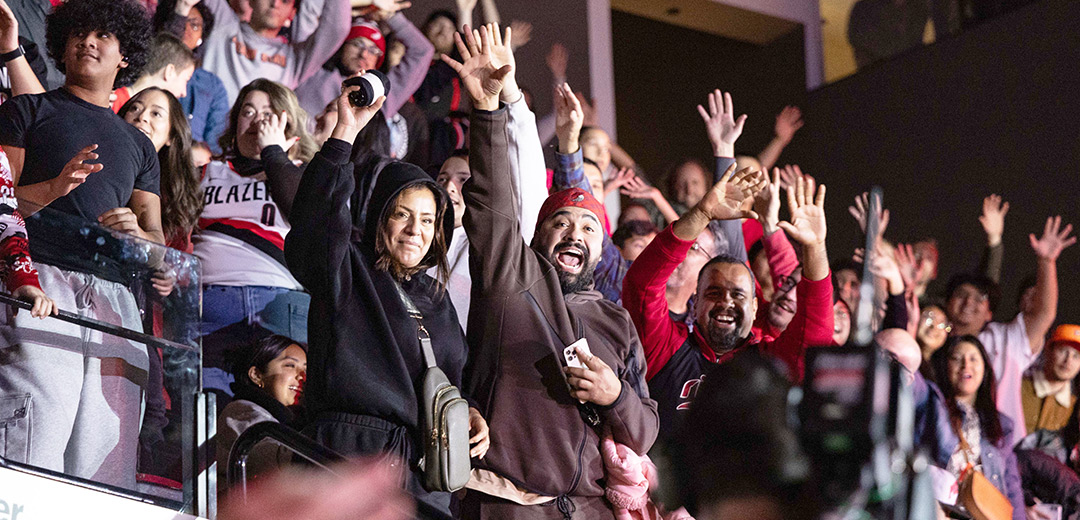 Excited Portland Trail Blazer fans cheer and acknowledge the camera.