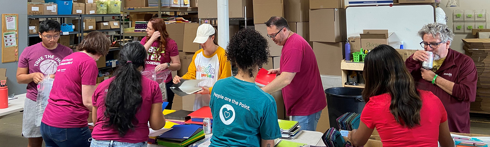 Volunteer Moda Health team reps pack school supplies for children.