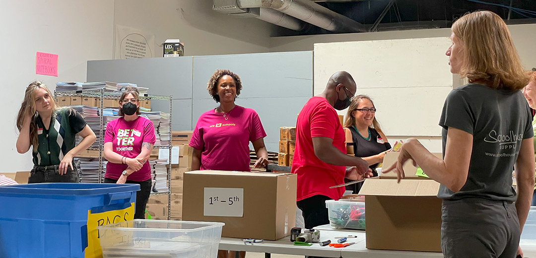 Volunteer Moda Health reps laugh as they work together packing helpful supplies for the community.