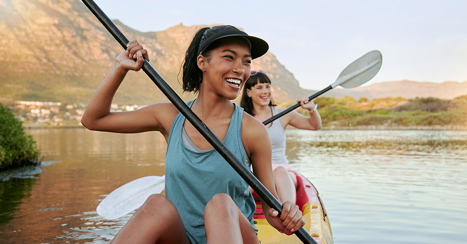 Two women kayaking on a lake, healthy and active