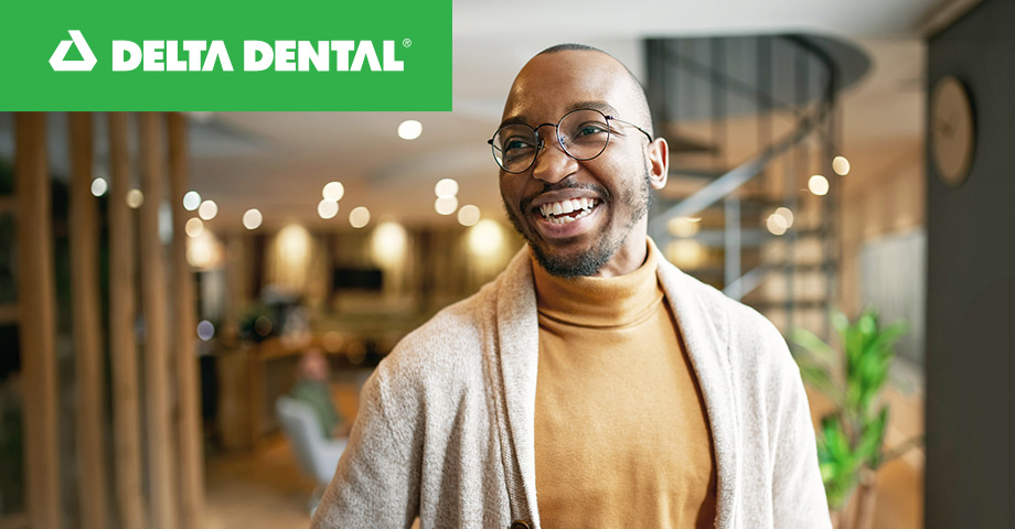 A man smiling with the delta dental logo in the corner of the photo