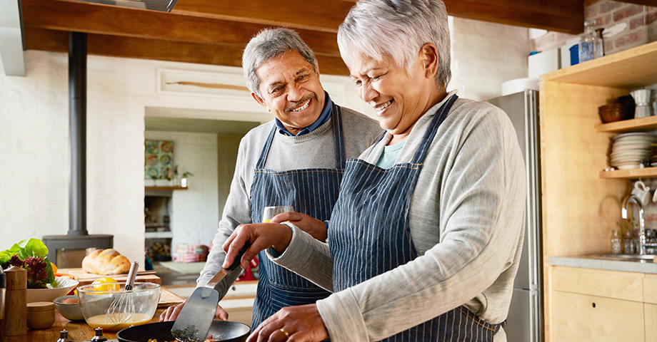 An older couple happily cooking together 
