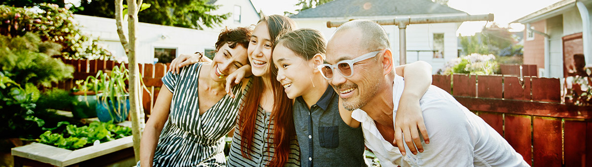 A family sitting outside in the sun with their arms around each other 