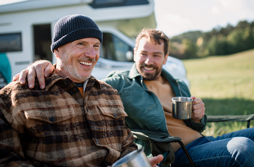 A father and son out camping enjoying a cup of coffee