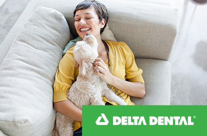 A young woman laying with her dog after getting Delta Dental insurance plans in either Oregon or Alaska.