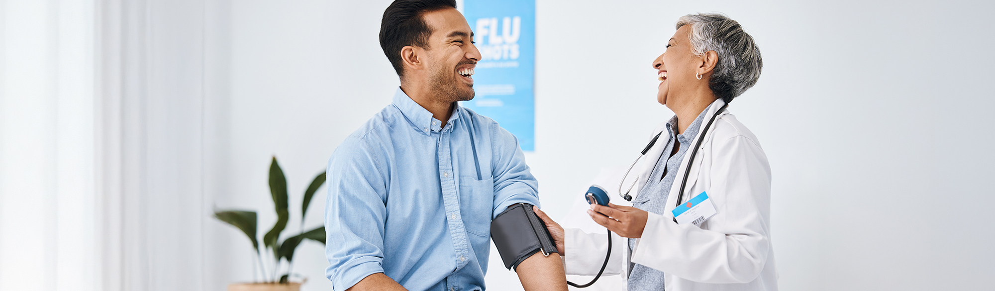 Female doctor getting blood pressure reading from a smiling male patient