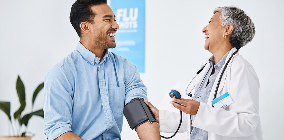 Female doctor getting blood pressure reading from a smiling male patient