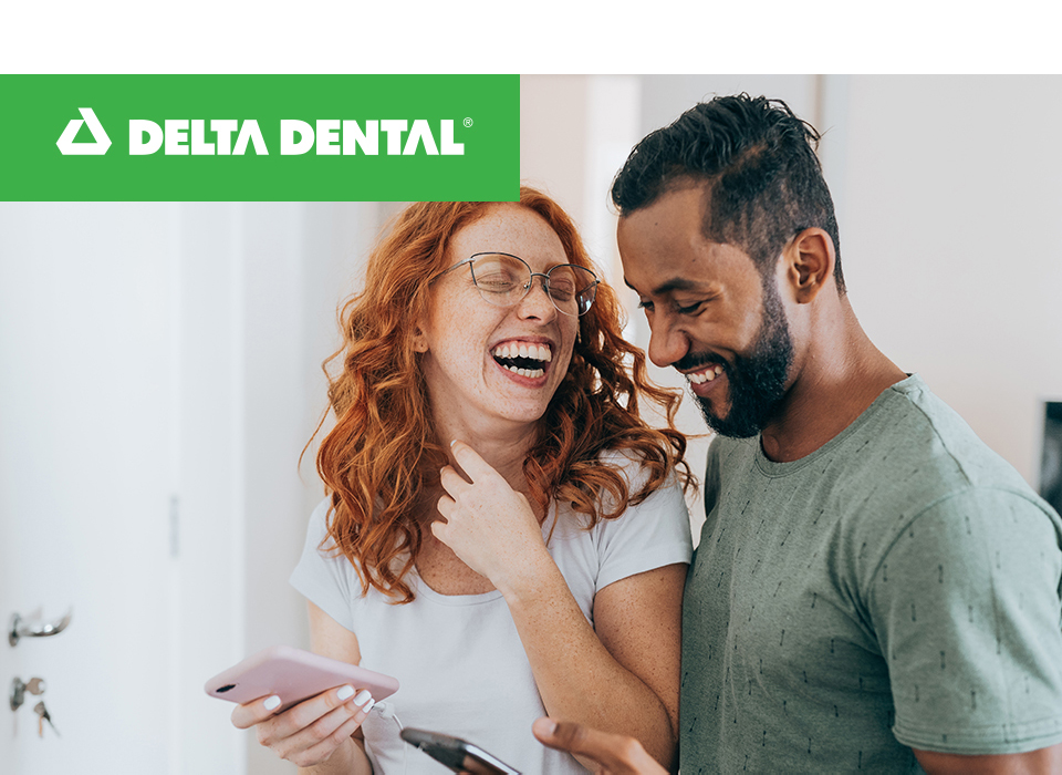  A couple looking at each other smiling and happy they have dental insurance