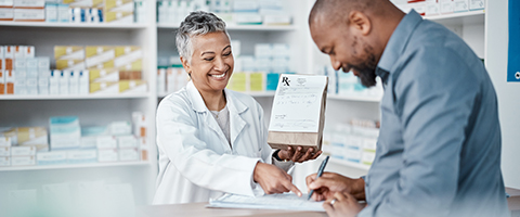 A customer filling out paperwork while being directed by a pharmacist